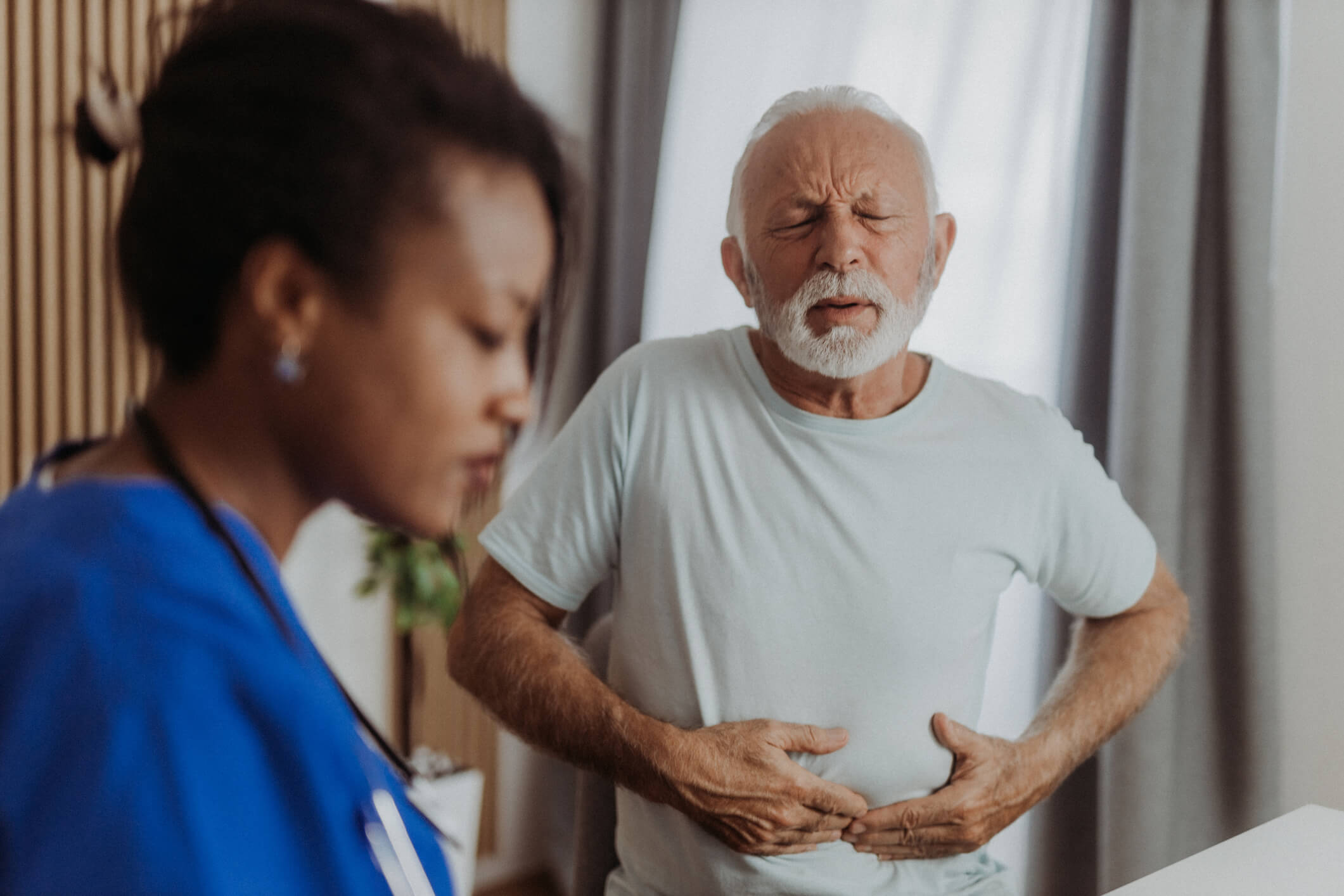 Elder man with stomach issues in doctor's office.