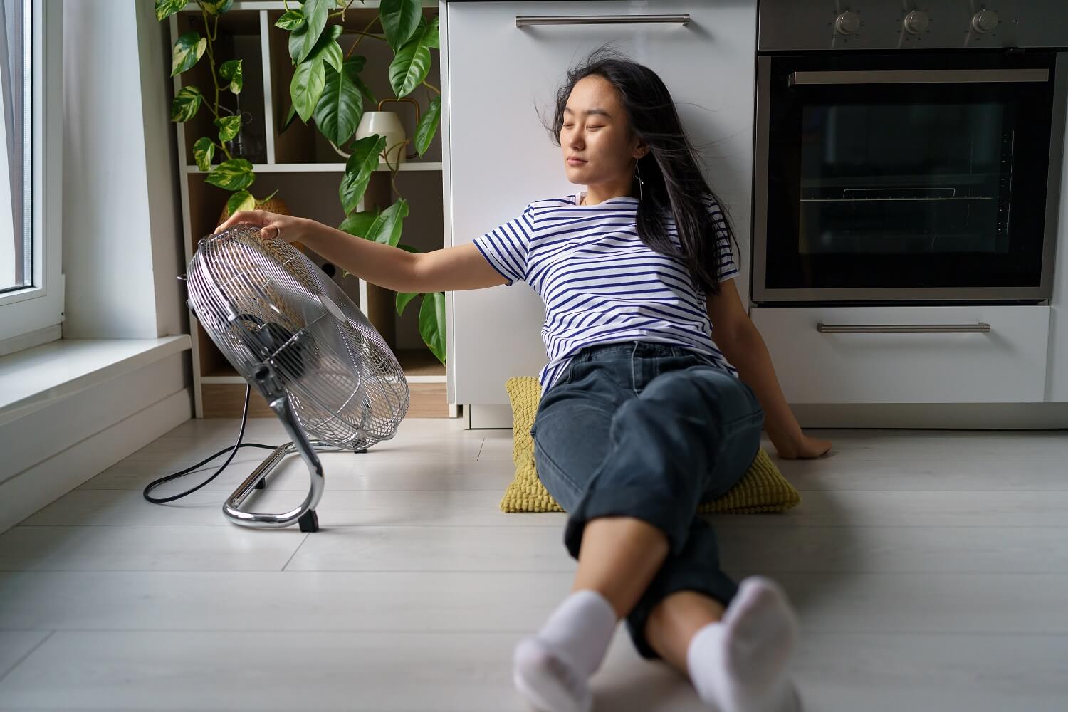 woman sitting on the floor next to fan