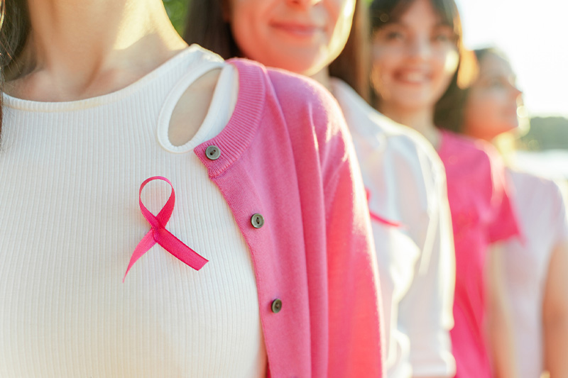 women standing wearing pink ribbon